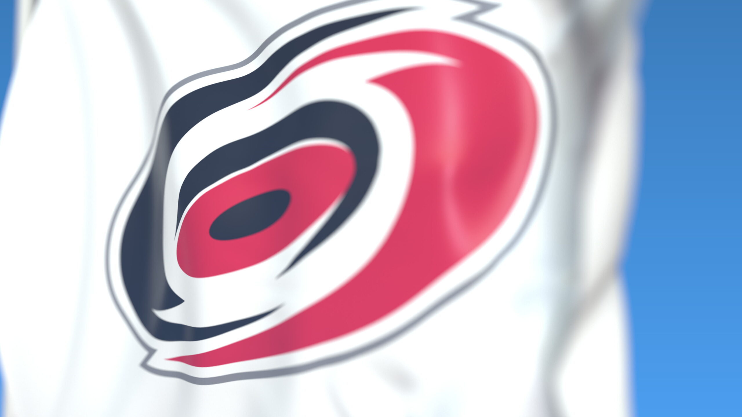 Close-up of white fabric with a bold red and navy circular logo, partially cropped against a blue background.