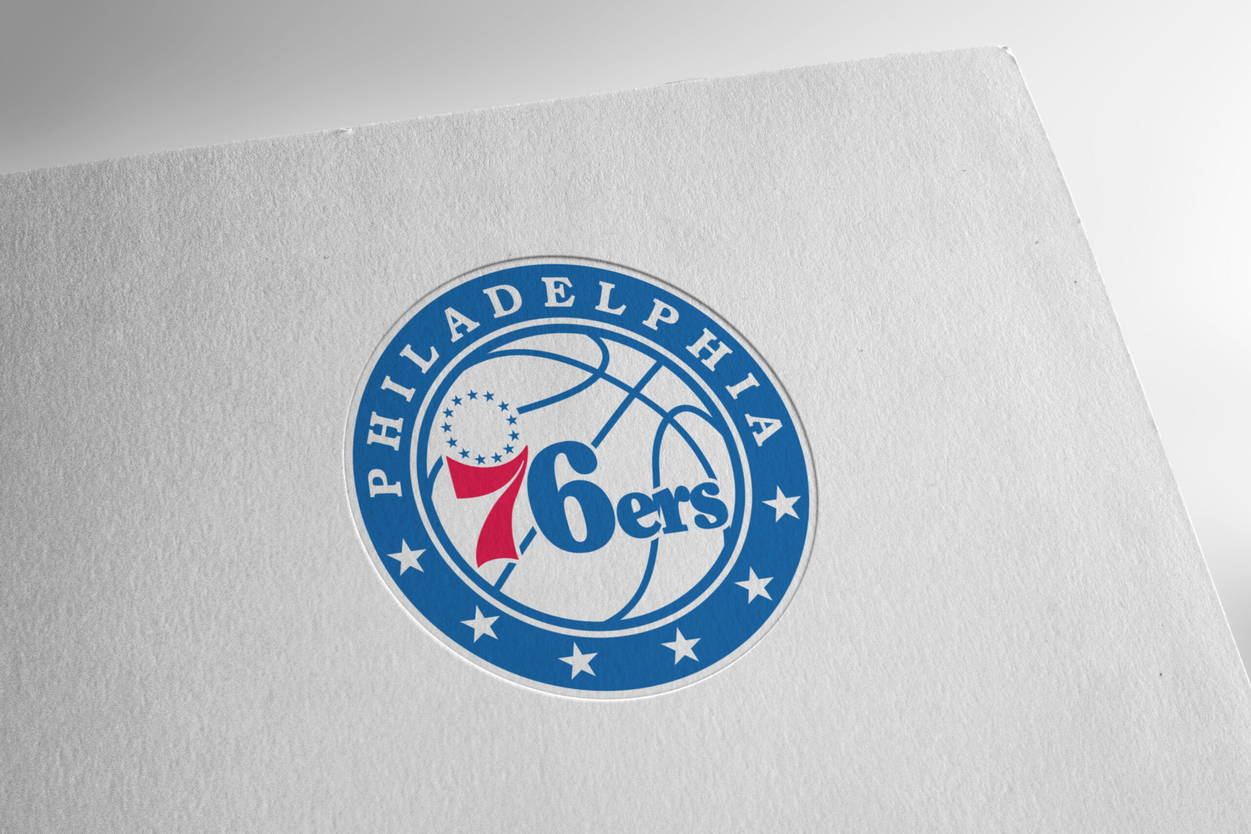 Circular Philadelphia 76ers logo on a textured white background, partially cropped by a tilted card edge